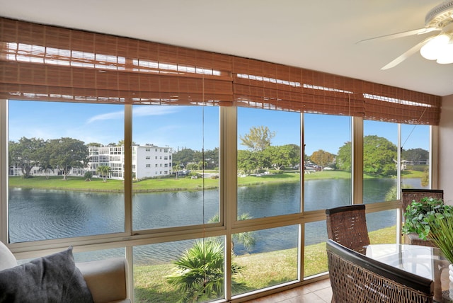 sunroom / solarium featuring ceiling fan, a healthy amount of sunlight, and a water view