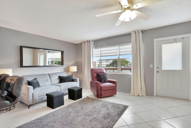 living room with ceiling fan, a textured ceiling, and light tile patterned floors