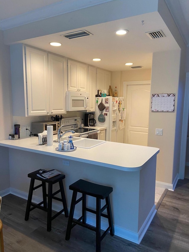 kitchen featuring white cabinetry, dark hardwood / wood-style flooring, white appliances, and kitchen peninsula