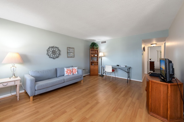 living room featuring a textured ceiling and light wood-type flooring