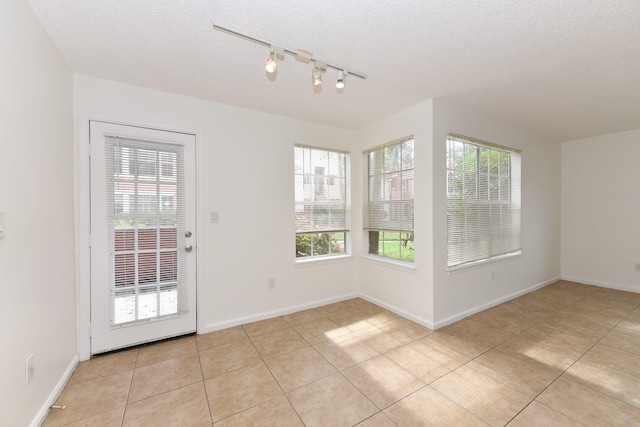 interior space featuring light tile patterned flooring, a healthy amount of sunlight, and a textured ceiling