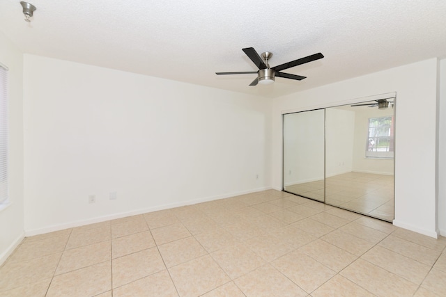 unfurnished bedroom with ceiling fan, a closet, a textured ceiling, and light tile patterned flooring