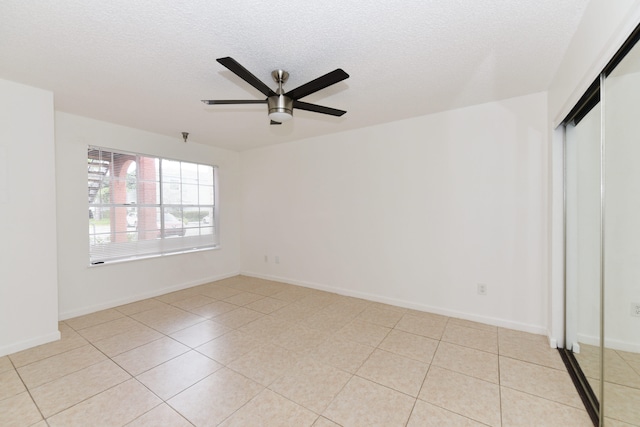 interior space with ceiling fan, light tile patterned flooring, and a textured ceiling