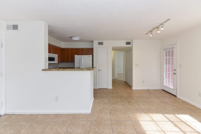 kitchen featuring light tile patterned flooring, white appliances, kitchen peninsula, and a textured ceiling