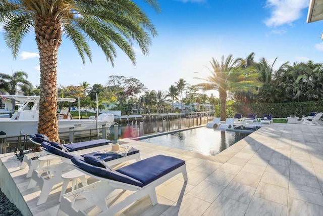 view of pool with a patio, a boat dock, and a water view