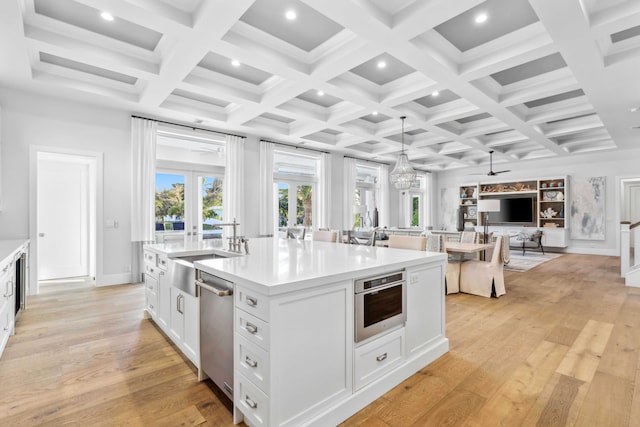 kitchen with pendant lighting, french doors, white cabinetry, a kitchen island with sink, and light hardwood / wood-style flooring