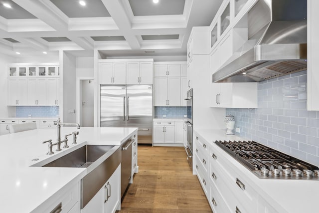 kitchen featuring stainless steel appliances, wall chimney range hood, white cabinets, and light hardwood / wood-style flooring