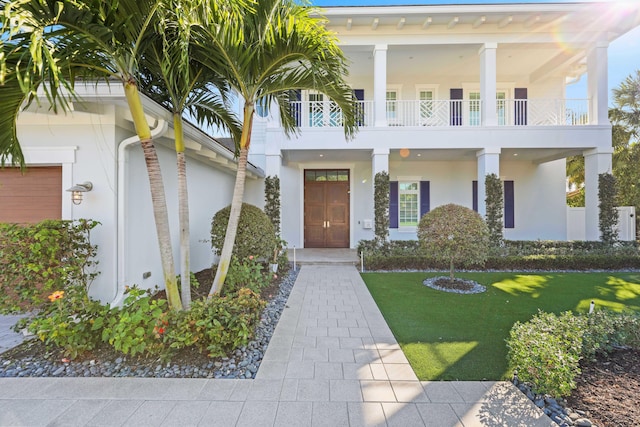 view of front of home with a garage, a front yard, and a balcony