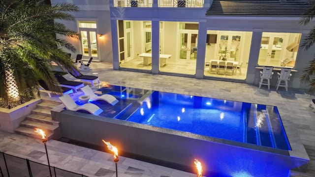 view of swimming pool with an outdoor fire pit, a patio area, and french doors