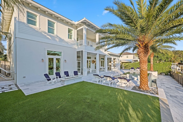 back of property with a patio area, french doors, a balcony, and a lawn