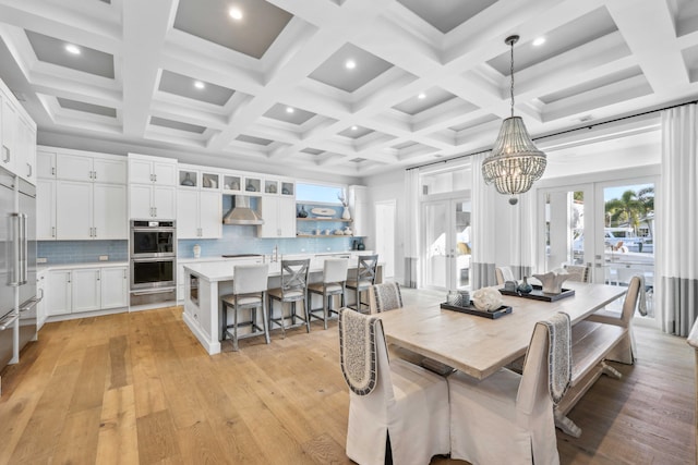 dining area featuring french doors, a chandelier, light hardwood / wood-style flooring, and beamed ceiling