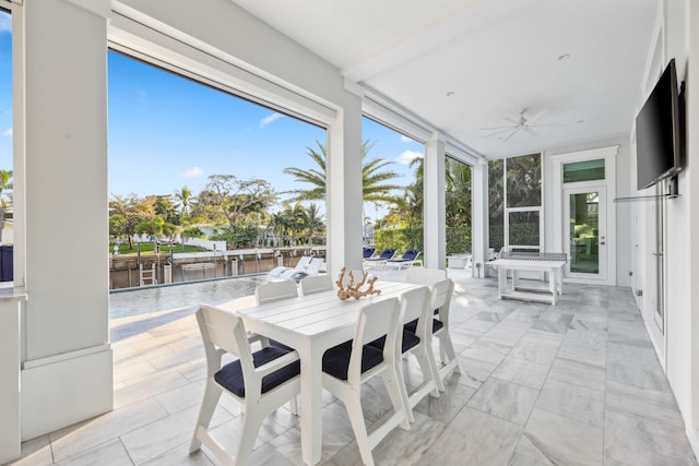 sunroom with a water view and ceiling fan