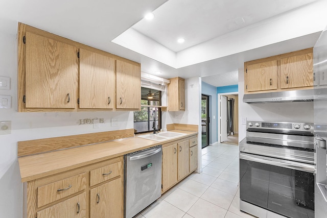 kitchen with under cabinet range hood, light countertops, light tile patterned floors, stainless steel appliances, and a sink