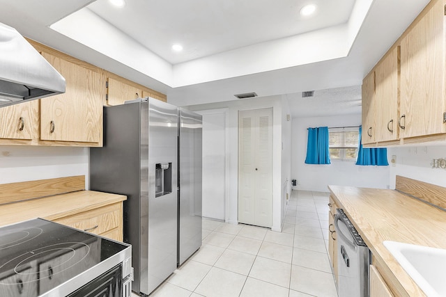 kitchen featuring light brown cabinetry, light tile patterned floors, appliances with stainless steel finishes, a raised ceiling, and island exhaust hood