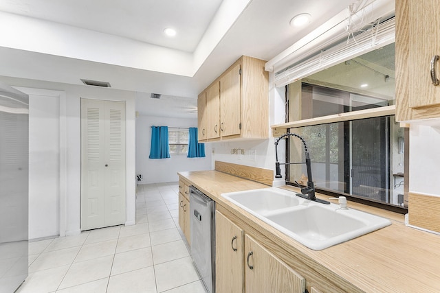 kitchen with light tile patterned flooring, sink, stainless steel dishwasher, and light brown cabinets