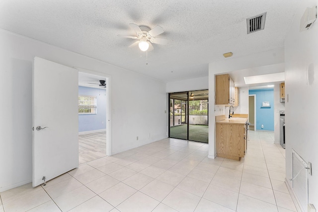 tiled empty room with a textured ceiling, a wealth of natural light, and ceiling fan