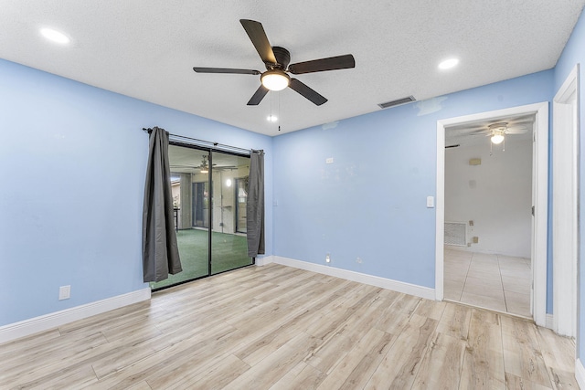 empty room featuring ceiling fan, a textured ceiling, and light hardwood / wood-style flooring