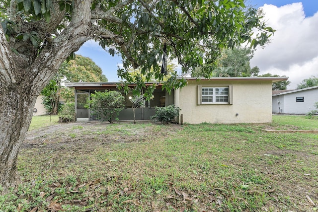 rear view of property with a sunroom and a yard