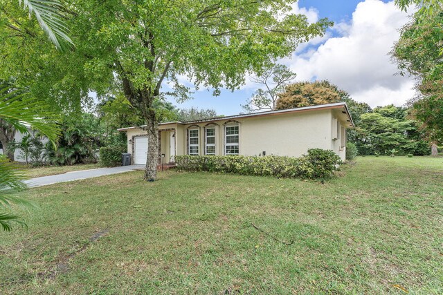 ranch-style home with concrete driveway, a garage, a front yard, and stucco siding