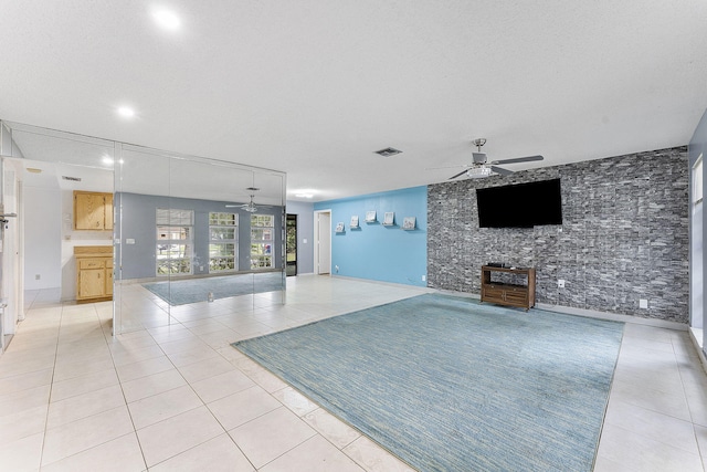 unfurnished living room featuring ceiling fan, a textured ceiling, and light tile patterned floors