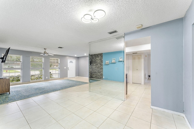 empty room featuring light tile patterned flooring, a textured ceiling, and ceiling fan