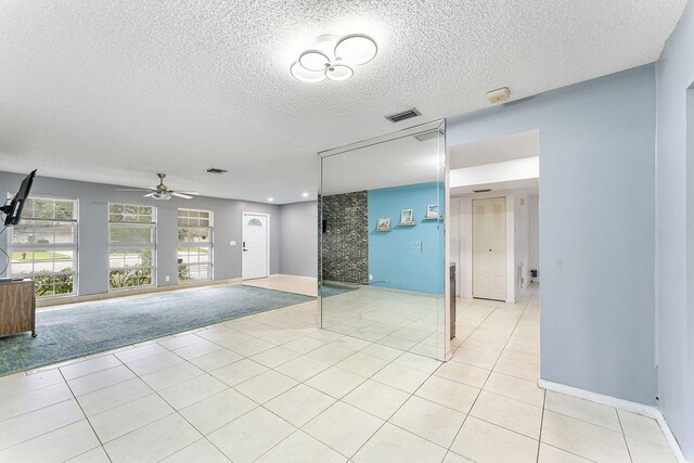 unfurnished living room with light tile patterned flooring, ceiling fan, and a textured ceiling