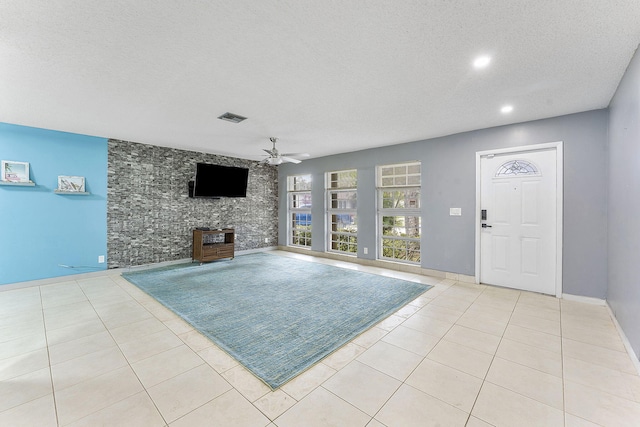 unfurnished living room featuring light tile patterned floors, a textured ceiling, and ceiling fan