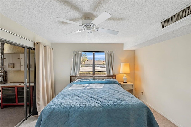 bedroom with ceiling fan, carpet floors, and a textured ceiling