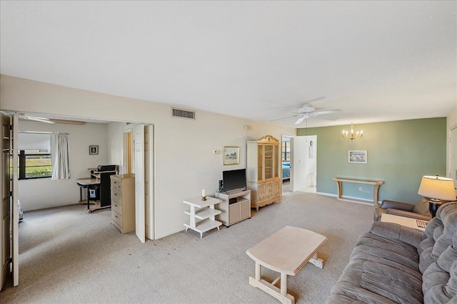 carpeted living room featuring ceiling fan with notable chandelier