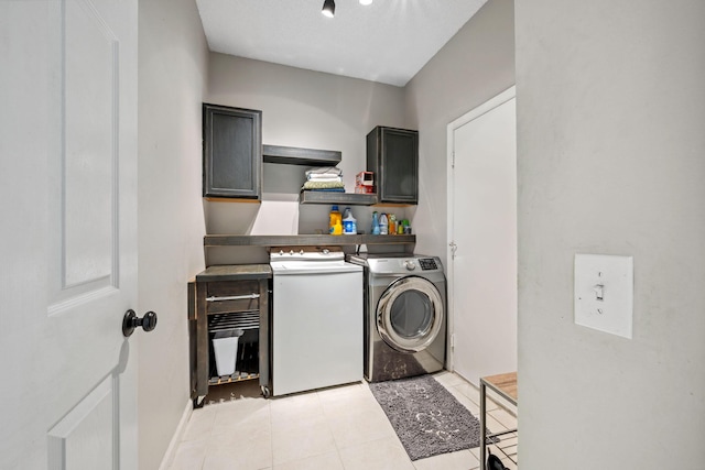 washroom with separate washer and dryer, light tile patterned floors, and cabinets