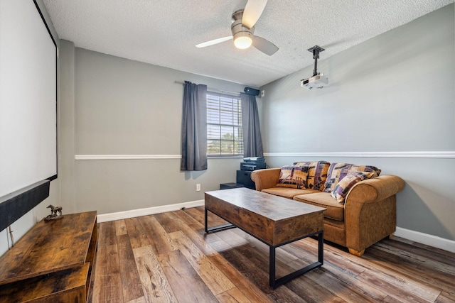 living room with hardwood / wood-style flooring, ceiling fan, and a textured ceiling