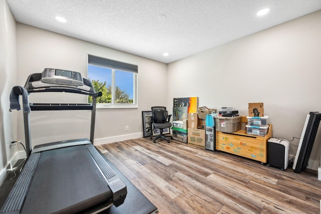 exercise area featuring hardwood / wood-style flooring and a textured ceiling