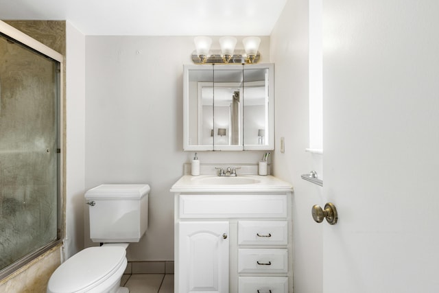 bathroom featuring tile patterned flooring, vanity, a shower with shower door, and toilet