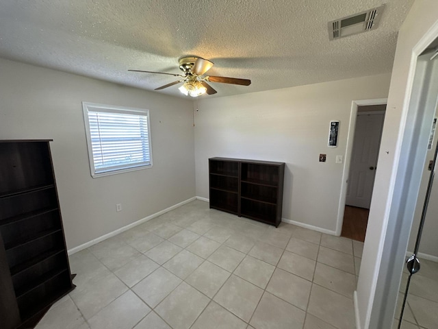 unfurnished bedroom with light tile patterned flooring, a textured ceiling, and ceiling fan