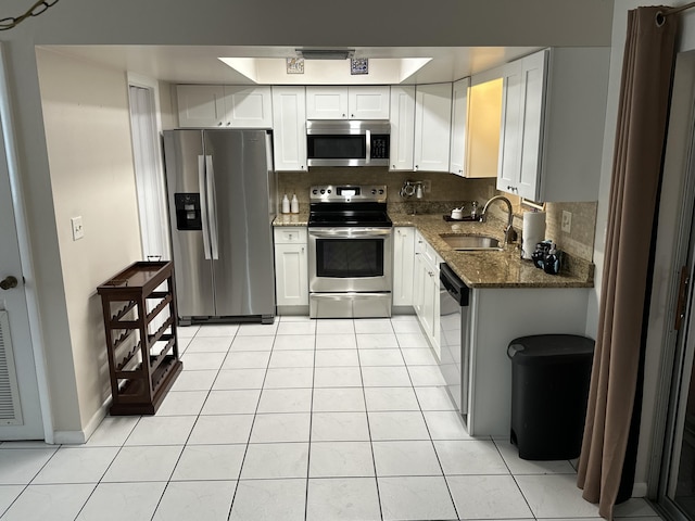 kitchen with sink, white cabinetry, light tile patterned floors, stainless steel appliances, and decorative backsplash