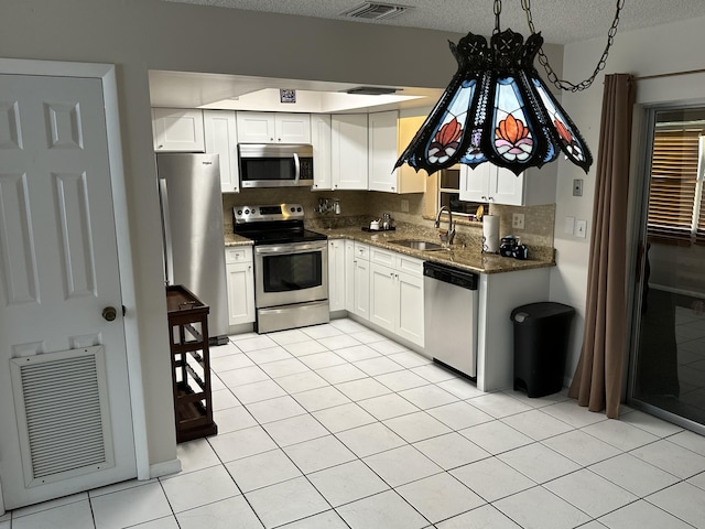 kitchen featuring appliances with stainless steel finishes, tasteful backsplash, white cabinetry, sink, and dark stone counters