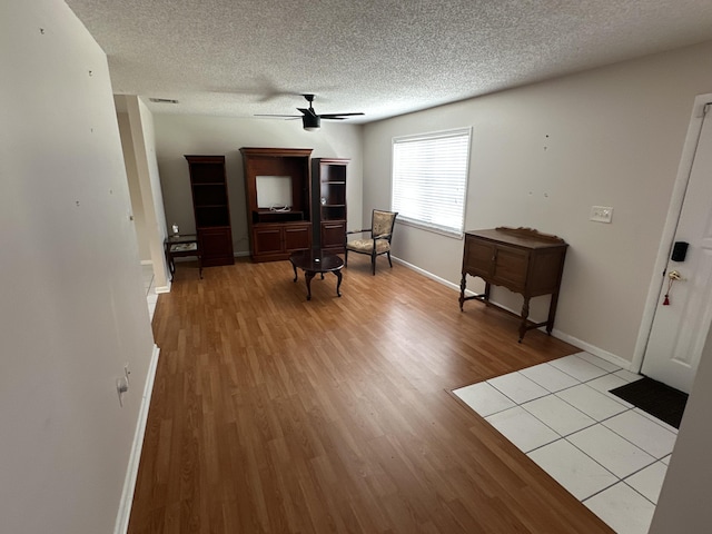 interior space with ceiling fan, a textured ceiling, and light hardwood / wood-style floors