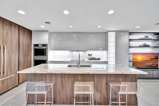 kitchen featuring white cabinetry, light stone countertops, and a breakfast bar area