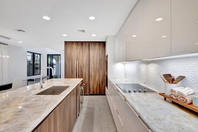 kitchen featuring light tile patterned flooring, white cabinetry, sink, decorative backsplash, and black electric cooktop