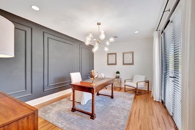 office with light hardwood / wood-style flooring and a chandelier