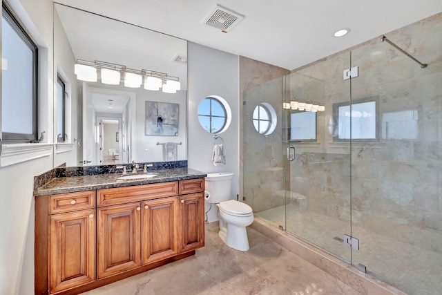 bathroom featuring a shower with door, vanity, and toilet