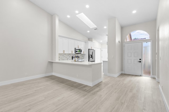 kitchen with white cabinetry, tasteful backsplash, a skylight, appliances with stainless steel finishes, and kitchen peninsula