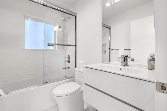 full bathroom featuring vanity, bath / shower combo with glass door, and toilet