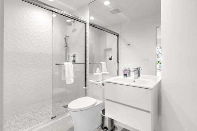 bathroom featuring vanity, toilet, and a shower with shower door