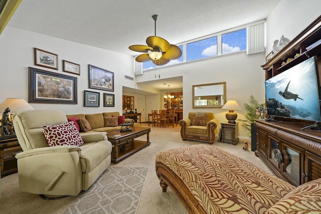 carpeted living room featuring ceiling fan with notable chandelier, a textured ceiling, and a high ceiling