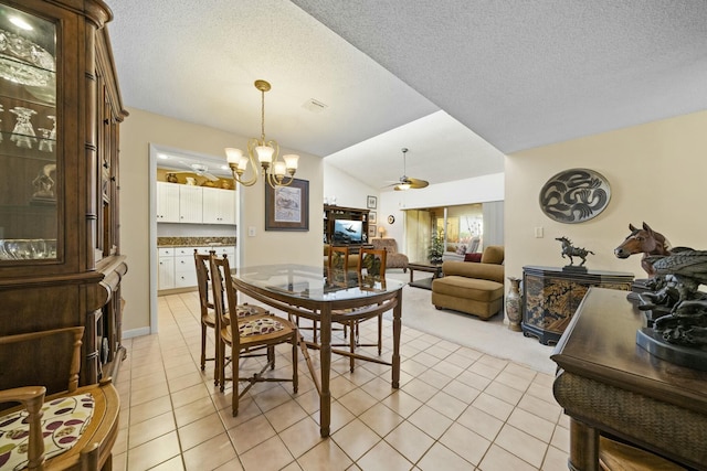 tiled dining room with ceiling fan with notable chandelier and a textured ceiling