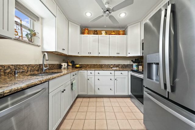 kitchen with appliances with stainless steel finishes, sink, white cabinets, and dark stone counters