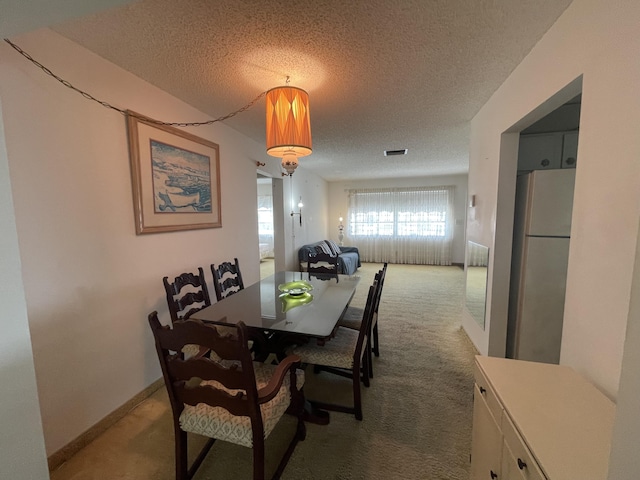 carpeted dining space featuring a textured ceiling