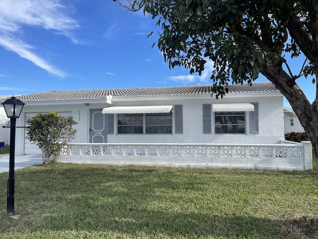 view of front of property featuring a garage, a front yard, and a tile roof