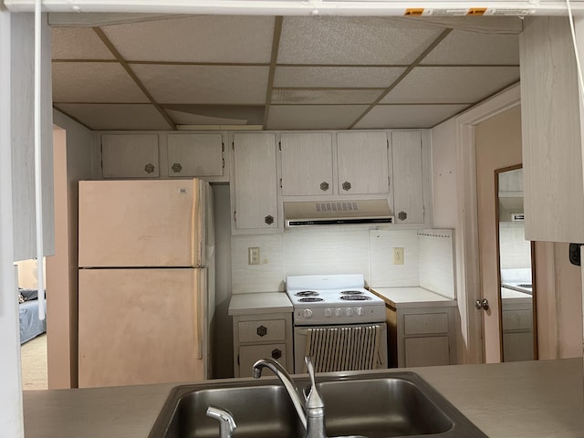 kitchen featuring electric range oven, refrigerator, sink, backsplash, and a drop ceiling